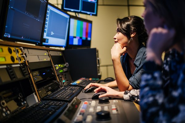In einem der Studios der Fakultät Informatik und Medien der HTWK Leipzig. (Foto: feinesbild.de) junge Frau sitzt in einem abgedunktelten Regie-Studio vor Bildschirmen